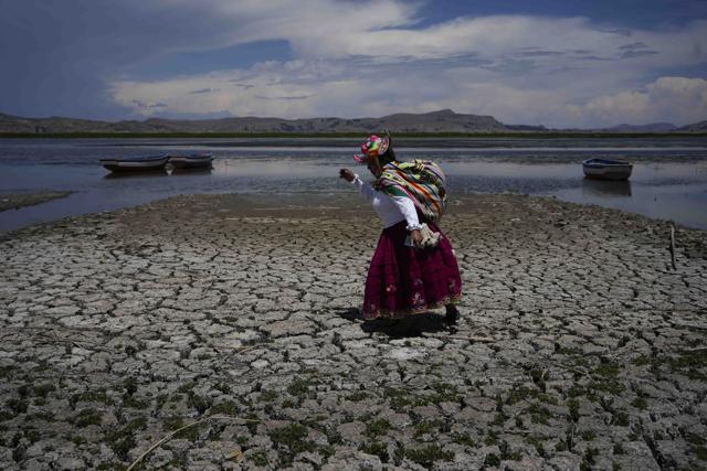 Eco-activist Maruja Inquilla walks on a dried out portion of Lake Titicaca in Peru in November, amid a winter heat wave. (AP) Eco-activist Maruja Inquilla walks on a dried out portion of Lake Titicaca in Peru in November, amid a winter heat wave. (AP)