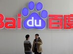 People talk in front of a Baidu's company logo at Baidu's headquarters in Beijing.