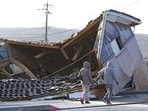 People walk by a building collapsed following an earthquake in Shikamachi, Ishikawa prefecture, Japan on January 2.