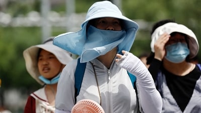 People wearing sun protection gear amid a heatwave walk on a street in Beijing, China. (Reuters)
