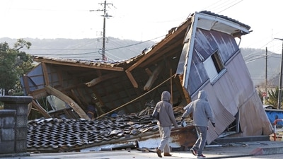 People walk by a building collapsed following an earthquake in Shikamachi, Ishikawa prefecture, Japan on January 2. (AP)
