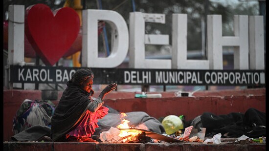 A woman warms herself with a bonfire on Tuesday. (Sanchit Khanna/HT Photo)