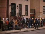 FILE - Migrants queue in the cold as they look for a shelter outside a migrant assistance center at St. Brigid Elementary School on Tuesday, Dec. 5, 2023, in New York. Nervous officials in suburbs and outlying cities near Chicago and New York are giving migrants arriving from the southern border a cold shoulder.  Edison, New Jersey, the mayor warned he would send people back to the border if they came to his city in buses. The moves come amid attempts to circumvent new limits on dropping migrants in the two cities, opening a new front in response to efforts led by Texas Gov. Greg Abbott to pay for migrants to leave his state. 