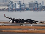 Officials investigate a burnt Japan Airlines (JAL) Airbus A350 plane after a collision with a Japan Coast Guard aircraft at Haneda International Airport in Tokyo