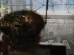 A Yamanote Line train conductor sits in a control room as another Yamanote Line train approaches.