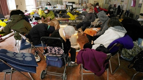 Evacuees rest surrounding a heater at a temporary evacuation center in Suzu. Relief officials were delivering water, blankets, food and other supplies.&nbsp;(AP)