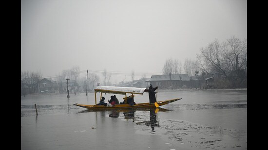 A man rows a boat on the partially frozen surface of the Dal Lake on a cold morning in Srinagar on Thursday. (Waseem Andrabi /HT)