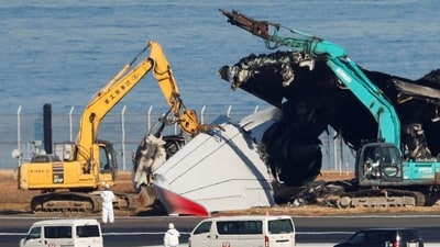Officials try to remove the wreckage of a burnt Japan Airlines (JAL) Airbus A350 plane after a collision with a Japan Coast Guard aircraft at Haneda International Airport in Tokyo. (Reuters)