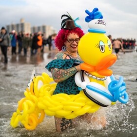 Holding her pretty inflatable duck, a woman is all smiles while embracing the freezing water on the Coney Islands, USA