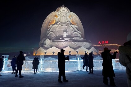 Visitors marvel at a snow sculpture of a giant Buddha
