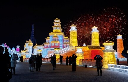 People watch fireworks explode over ice sculptures at the opening ceremony