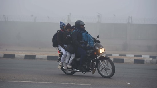 Students are going to school amid cold and dense foggy weather at South West Delhi near Samalka red light, in New Delhi, India, on Wednesday, 27 December 2023. (Photo by Parveen Kumar/Hindustan Times)