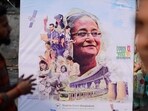 People stand next to a campaign poster of the ruling party during parliamentary election in Dhaka, Bangladesh, Sunday, Jan 7, 2024. People stand next to a campaign poster of the ruling party during parliamentary election in Dhaka, Bangladesh, Sunday, Jan 7, 2024.