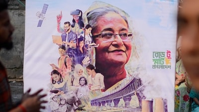 People stand next to a campaign poster of the ruling party during parliamentary election in Dhaka, Bangladesh, Sunday, Jan 7, 2024. (AP) People stand next to a campaign poster of the ruling party during parliamentary election in Dhaka, Bangladesh, Sunday, Jan 7, 2024. (AP)