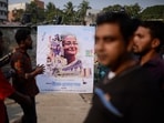 People stand next to a campaign poster of the ruling party during parliamentary election in Dhaka, Bangladesh, Sunday, Jan 7, 2024.(AP)