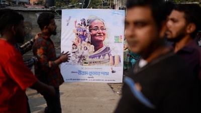 People stand next to a campaign poster of the ruling party during parliamentary election in Dhaka, Bangladesh, Sunday, Jan 7, 2024. (AP) People stand next to a campaign poster of the ruling party during parliamentary election in Dhaka, Bangladesh, Sunday, Jan 7, 2024. (AP)