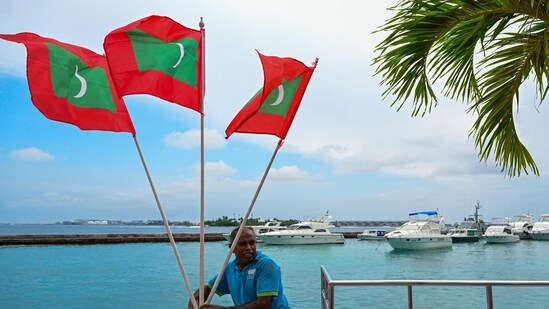 A worker carries national flags of Maldives in Male. (AFP)