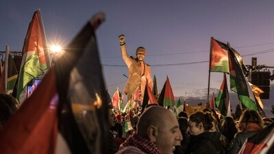 People raise flags and placards as they gather around a statue of late South African president Nelson Mandela to celebrate a landmark "genocide" case filed by South Africa against Israel. (AFP) People raise flags and placards as they gather around a statue of late South African president Nelson Mandela to celebrate a landmark "genocide" case filed by South Africa against Israel. (AFP)