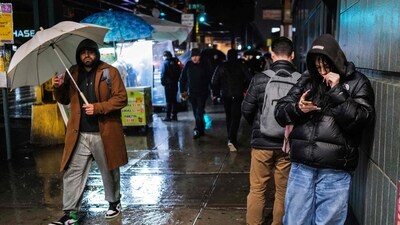 People walk in a street of the Queens borough of New York city on January 9, 2024, as a major storm system was battering parts of the United States (Photo by Charly TRIBALLEAU / AFP) (AFP)