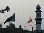 This photograph taken on December 28, 2023 shows a flag depicting the Hindu deities Ram and Hanuman waving on a rooftop beside a mosque in Ayodhya. 