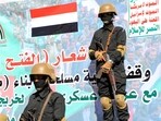 Huthi-affiliated Yemeni fighters stand guard in front of a banner. Huthi-affiliated Yemeni fighters stand guard in front of a banner.