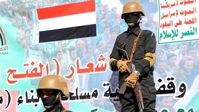 Huthi-affiliated Yemeni fighters stand guard in front of a banner. (AFP) Huthi-affiliated Yemeni fighters stand guard in front of a banner. (AFP)