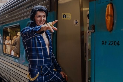 An Elvis impersonator gestures as he boards a train to travel | Photo: AFP