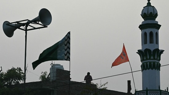 This photograph taken on December 28, 2023 shows a flag depicting the Hindu deities Ram and Hanuman waving on a rooftop beside a mosque in Ayodhya. (AFP)