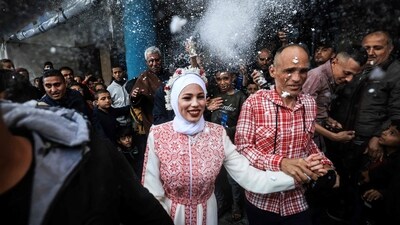 Israel-Hamas War: Palestinian bride Afnan Jibril (C) is escorted by her father (C-R) during her wedding at the UNRWA School in the al-Salam neighborhood of Rafah, southern Gaza Strip. (AFP) Israel-Hamas War: Palestinian bride Afnan Jibril (C) is escorted by her father (C-R) during her wedding at the UNRWA School in the al-Salam neighborhood of Rafah, southern Gaza Strip. (AFP)