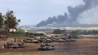 Israel-Hamas War: Israeli soldiers stand next to tanks at a position in Israel near the border with the Gaza Strip as smoke billows over the Gaza Strip after Israeli bombardment. (AFP) Israel-Hamas War: Israeli soldiers stand next to tanks at a position in Israel near the border with the Gaza Strip as smoke billows over the Gaza Strip after Israeli bombardment. (AFP)