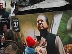 Pakistan elections: People walk past a banner of the Pakistan Muslim League Nawaz (PML N) party with an image of former prime minister of Pakistan and candidate Nawaz Sharif in Lahore.