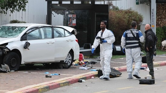 Israeli police forensics personnel inspect a damaged car following a suspected ramming attack in the central town of Raanana. (AFP)