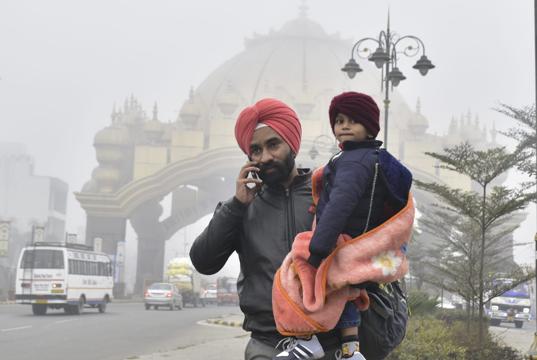 A father and son at Amritsar on Monday morning. Amritsar recorded a minimum of 5.7°C. (Sameer Sehgal/HT)