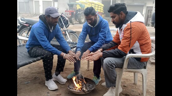 People sit by a bonfire in Malout onTuesday. Intense cold wave conditions prevailed in Punjab and Haryana on Tuesday, with Ballowal Saunkhri in Shaheed Bhagat Singh Nagar district recording a low of minus 0.4 degree Celsius. (Sanjeev Kumar /HT)