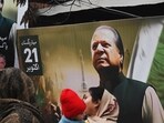 Pakistan elections: People walk past a banner of the Pakistan Muslim League Nawaz (PML N) party with an image of former prime minister of Pakistan and candidate Nawaz Sharif in Lahore.