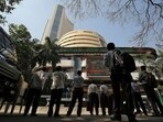 People look at a screen displaying the Sensex results on the facade of the Bombay Stock Exchange (BSE) building in Mumbai.