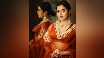 Styled by Lakshmi Lehr and Gaurviv Desai, Rashmika's terracotta lehenga is from Devnaagri. It features a sleeveless choli, a lehenga skirt, and an organza lehenga. While the blouse has an open back design, a plunging V neckline, a cropped hem, tassel-adorned dori ties on the back, and a fitted bust, the lehenga has gold gota patti embroidery on the waist and hem, pleated A-line silhouette, and a floor-length hem. Lastly, the gold dori in floral motifs added a dreamy touch to the ensemble. (Instagram) Styled by Lakshmi Lehr and Gaurviv Desai, Rashmika's terracotta lehenga is from Devnaagri. It features a sleeveless choli, a lehenga skirt, and an organza lehenga. While the blouse has an open back design, a plunging V neckline, a cropped hem, tassel-adorned dori ties on the back, and a fitted bust, the lehenga has gold gota patti embroidery on the waist and hem, pleated A-line silhouette, and a floor-length hem. Lastly, the gold dori in floral motifs added a dreamy touch to the ensemble. (Instagram)