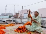 A woman makes garlands at her house in Ayodhya as the construction site of Ram Temple is seen in the background. (REUTERS)