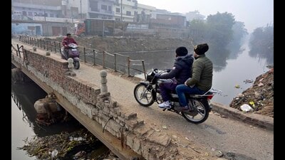 Commuters crossing the damaged bridge on Buddha Nullah located in Shivpuri area in Ludhiana. (HT) Commuters crossing the damaged bridge on Buddha Nullah located in Shivpuri area in Ludhiana. (HT)
