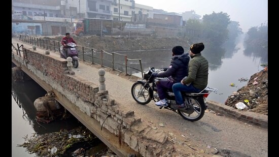 Commuters crossing the damaged bridge on Buddha Nullah located in Shivpuri area in Ludhiana. (HT)