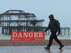 A man walks past a public information sign on the beach ahead of the arrival of Storm Jocelyn, in Brighton, Britain. Storm Jocelyn batters the UK, disrupts travel and energy infrastructure across northwest Europe 