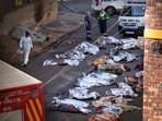 Medics stand by the covered bodies of victims of a deadly blaze in downtown Johannesburg, Thursday, Aug. 31, 2023.