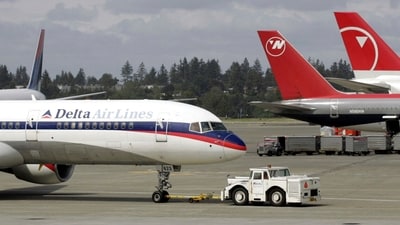 FILE - A Delta Airlines jet is pulled into position at left next to aircraft operated by Northwest Airlines. (AP Photo/Ted S. Warren, File) (AP) FILE - A Delta Airlines jet is pulled into position at left next to aircraft operated by Northwest Airlines. (AP Photo/Ted S. Warren, File) (AP)
