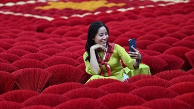 In this photo taken on January 20, 2024 a tourist takes a selfie picture in front of incense sticks arranged in the form of a Vietnamese flag in a courtyard in the village of Quang Phu Cau on the outskirts of Hanoi. Families living and working in the "incense village" of Quang Phu Cau now also make sticks in yellow, blue and green, catering to visitors eager to snap shots for Instagram. (Photo by Nhac NGUYEN / AFP) In this photo taken on January 20, 2024 a tourist takes a selfie picture in front of incense sticks arranged in the form of a Vietnamese flag in a courtyard in the village of Quang Phu Cau on the outskirts of Hanoi. Families living and working in the "incense village" of Quang Phu Cau now also make sticks in yellow, blue and green, catering to visitors eager to snap shots for Instagram. (Photo by Nhac NGUYEN / AFP)