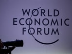 A press photographer works next to the logo of the World Economic Forum (WEF) at the opening of their annual meeting in Davos on January 15, 2024. 