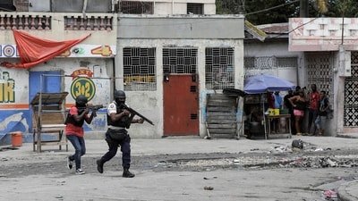 People huddle in a corner as police patrol the streets after gang members tried to attack a police station, in Port-au-Prince, Haiti. (Reuters)