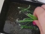A still of women frying these green toothpicks from a video on Twitter