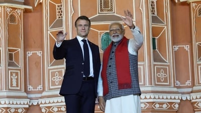 Prime Minister Narendra Modi and French President Emmanuel Macron wave during a roadshow in Jaipur. (via REUTERS)