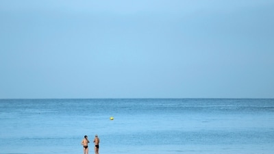 Two men talk together on the shore after swimming in the sea at La Concha beach in San Sebastian on January 26, 2024 as temperatures around 30�C were recorded in Spain. Spain is affected by a heat wave worthy of the start of summer in the middle of January, according to the meteorological agency (Aemet), which is worried about this "anomaly" . (Photo by ANDER GILLENEA / AFP) (AFP)