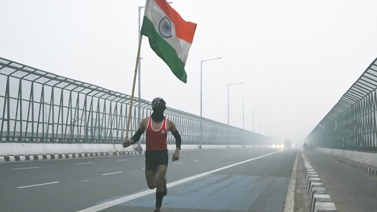 A man runs carrying India's national flag on occasion of Republic Day celebrations in New Delhi on January 26.(AFP)